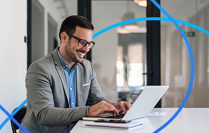 Hombre sonriendo mientras usa una laptop y un monitor